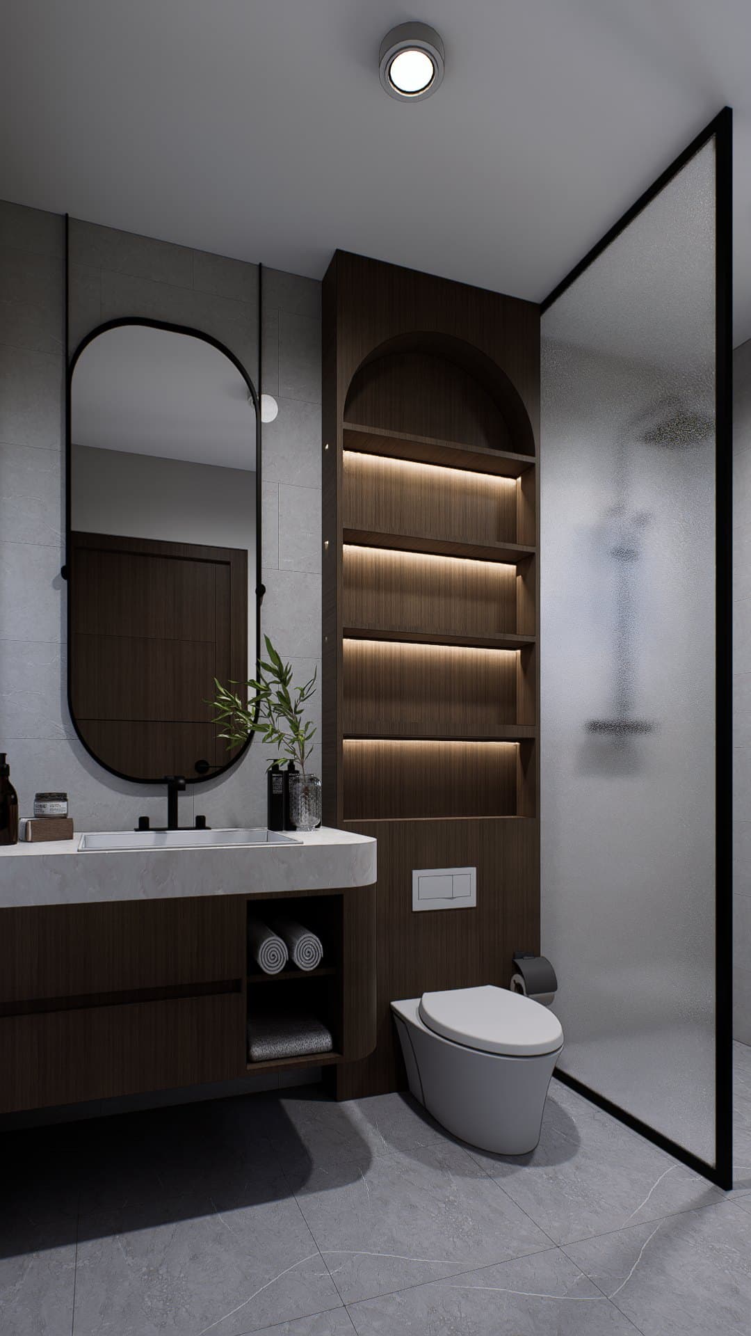 A bathroom in tonal tile, finished with a wall-hung vanity, glass shower screen and warm overhead lighting.